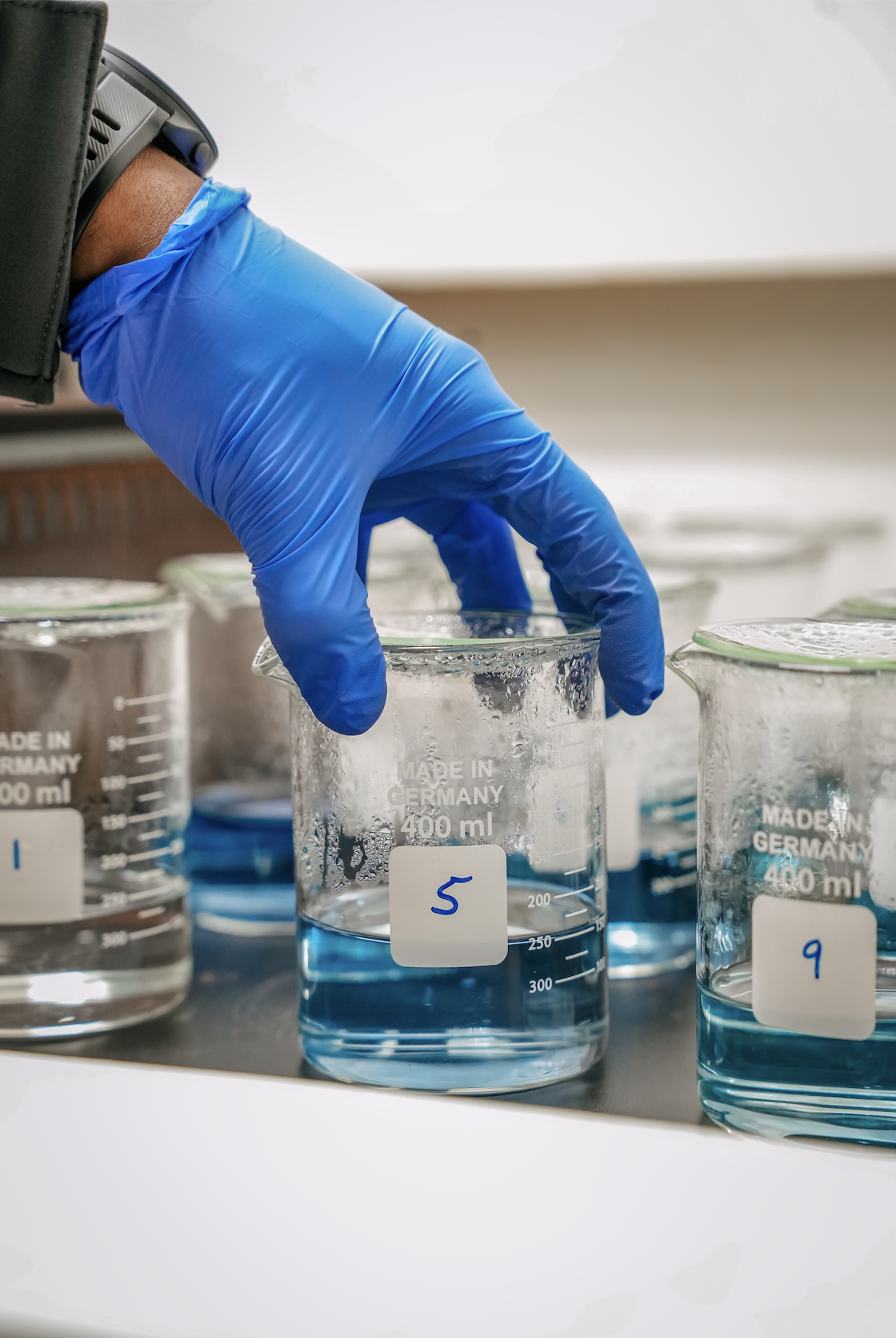 Hand holding beaker with blue liquid